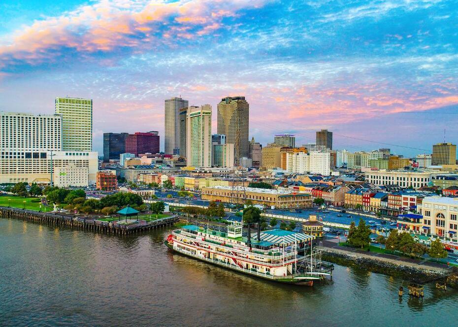 A boat on the water with the New Orleans, Louisiana skyline in the background.